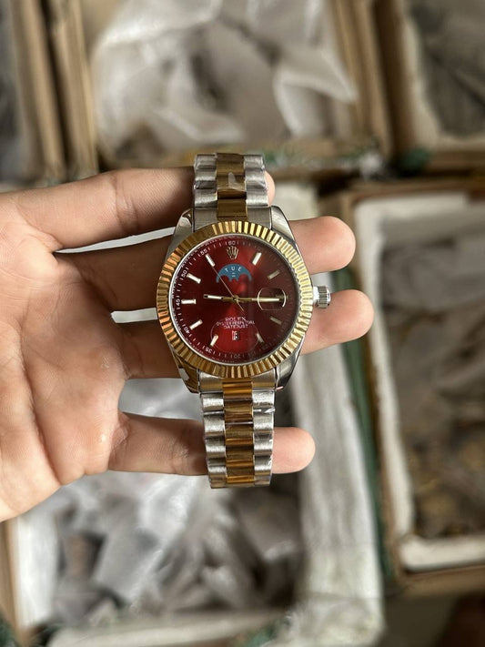 Rolex Gold and silver watch with a red face held in a hand against a blurred background